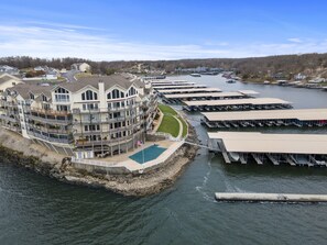 Een hotel aan het water met meerdere balkons, een zwembad en aangemeerde boten.
