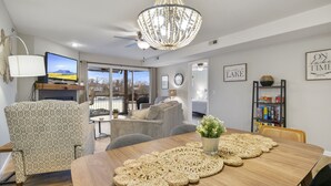 Uma sala de estar moderna com uma mesa de jantar de madeira, poltrona estampada e um lustre.