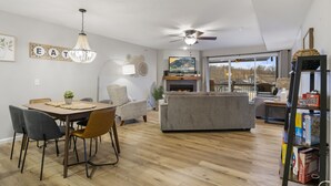 Uma sala de estar moderna com lareira, uma área de jantar com mesa e cadeiras, e uma estante de livros.