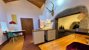 Une cuisine moderne avec une arche en pierre, une table à manger en bois et un récipient rouge.