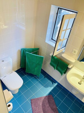 Une salle de bain avec des toilettes, un lavabo et une fenêtre.