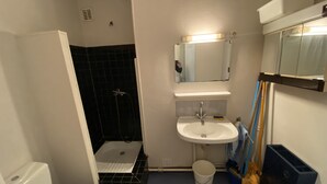 A bathroom with a toilet, sink, shower, and a mirror. - Studio at the foot of the slopes Laguiole resort (Laguiole)