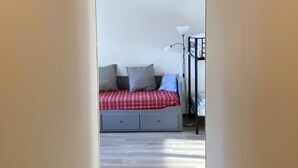 A narrow hallway leading to a bedroom with a bed, a nightstand, and a lamp. - Studio at the foot of the slopes Laguiole resort (Laguiole)