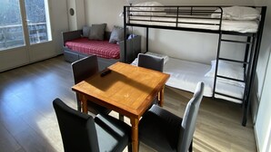 A compact room with a wooden table and chairs, a bunk bed, a sofa, and a window with a view. - Studio at the foot of the slopes Laguiole resort (Laguiole)