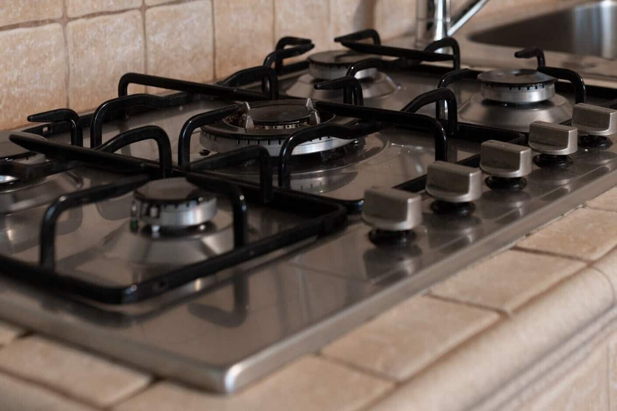A kitchen with a gas stove, a sink, and a tiled backsplash.