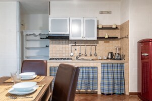 A kitchen with white cabinets, a red refrigerator, and a dining table set with plates and a glass.