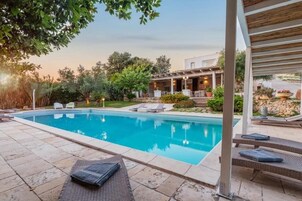 A swimming pool with lounge chairs and a pergola.
