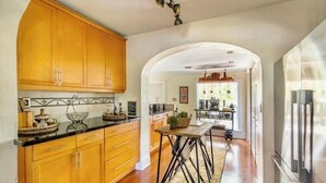 Een keuken met houten kastjes, een zwart aanrecht en een centraal kookeiland met een tafel en stoelen.