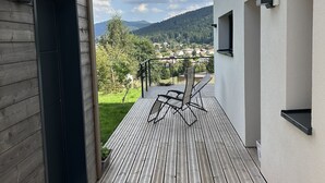 Una terraza de madera con vistas a un pueblo y montañas.
