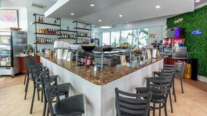 A bar area with a counter, chairs, shelves with bottles, and a green wall.
