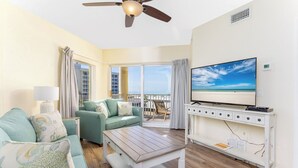 A living room with a sofa, a coffee table, a TV, and a balcony with a view.