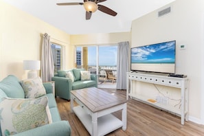 A living room with a sofa, a coffee table, a TV, and a balcony with a view.