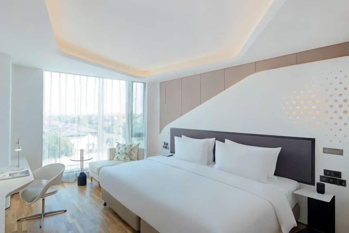 Ein modernes Hotelzimmer mit einem großen Bett, einem Schreibtisch und einem Stuhl.