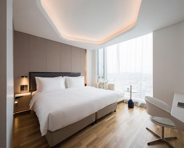 A modern hotel room with a large bed, a desk, and a view of the city. - Fly Zoo Hotel (Hangzhou)