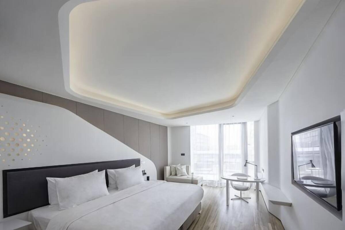 Ein modernes Hotelzimmer mit einem großen Bett, einem Schreibtisch und Blick auf die Stadt.