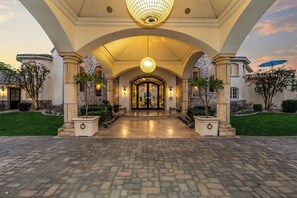 A grand entrance with a stone facade, arched columns, and a large chandelier.