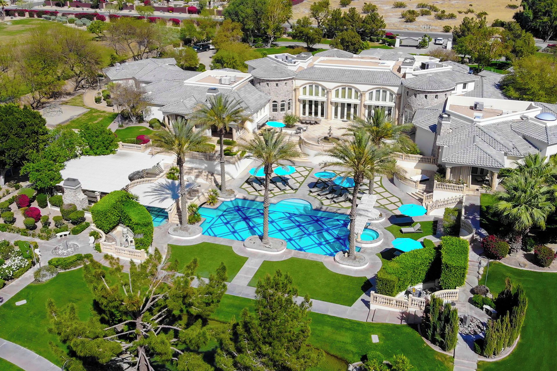 A large estate with a swimming pool, palm trees, and a well-maintained lawn.