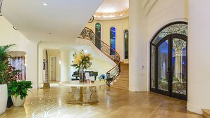 A grand foyer with a marble floor, a central round table, and a spiral staircase. - Chateau Dumont - 15 bedroom mansion (Rancho Mirage)