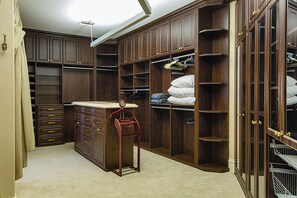 A walk-in closet with multiple shelves, drawers, and hanging space.