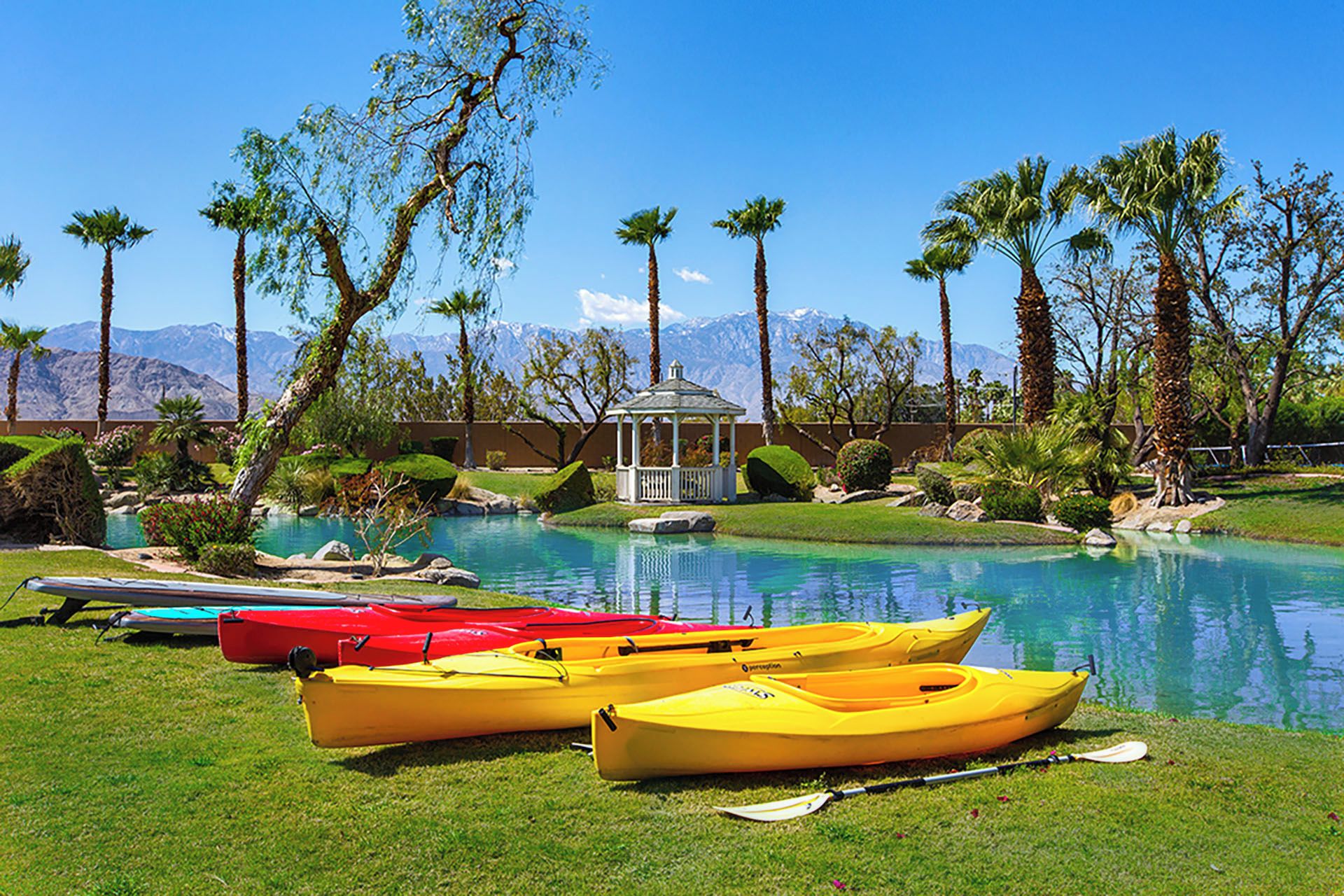 A pool area with kayaks, a gazebo, and palm trees.