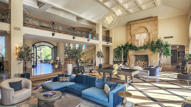 A spacious lobby with a high ceiling, a grand staircase, and a fireplace. - Chateau Dumont - 15 bedroom mansion (Rancho Mirage)