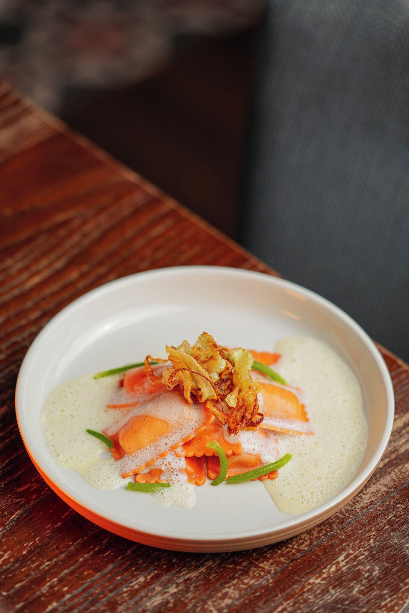 A white plate with a dish of food, possibly salmon, on a wooden table.