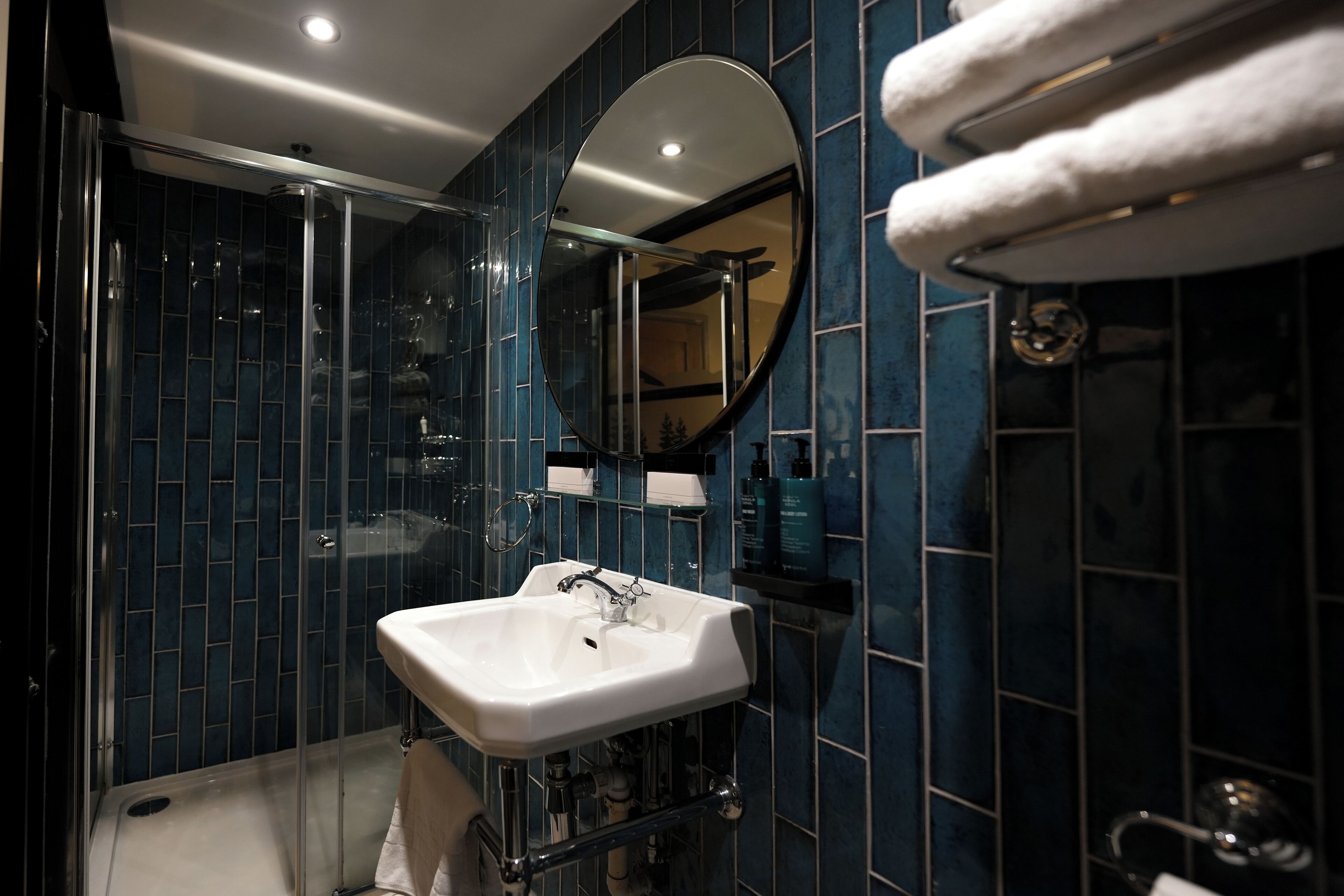 A modern bathroom with a glass-enclosed shower, a white sink, and a large mirror.