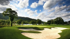 A golf course with sand bunkers, trees, and a lake in the background. - Riva Boutique Hotel & Restaurant (Helensburgh)