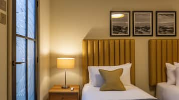 A hotel room with a bed, bedside table, lamp, and two framed pictures on the wall.