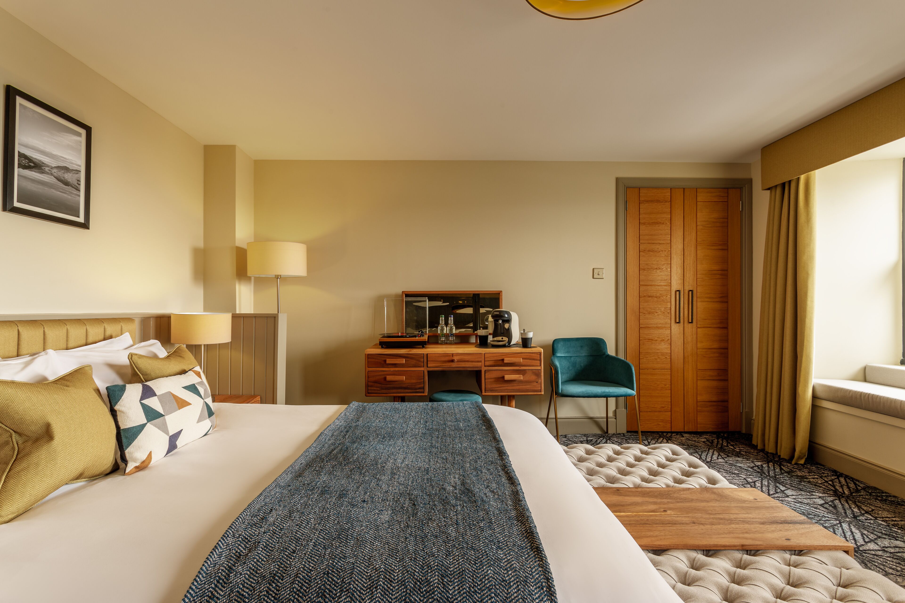 A hotel room with a bed, a desk, a chair, a wardrobe, and a window with curtains.