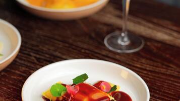 A dining table with a plate of ravioli and a glass of wine.