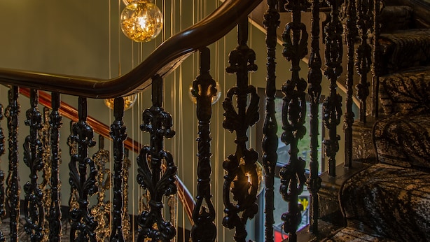 A staircase with ornate metal railings and hanging spherical light fixtures. - Riva Boutique Hotel & Restaurant (Helensburgh)