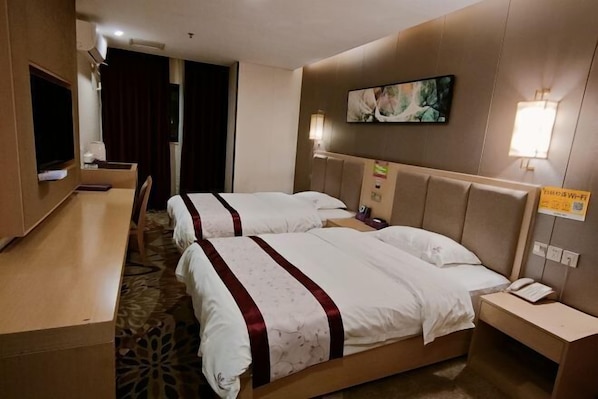 A hotel room with two beds, a desk, a TV, and a painting on the wall.