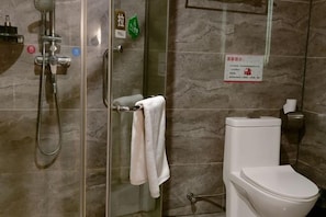A bathroom with a glass-enclosed shower, a toilet, and a towel rack.