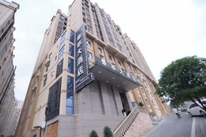Edifício com vários andares, entrada destacada e sinalização.