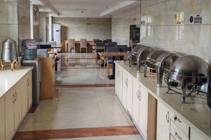 A modern hotel kitchen with a buffet setup, including stainless steel appliances and a long counter. - Zheng'an Manfei Hotel (Guitar Culture Squaie Branch) (Zheng'an)