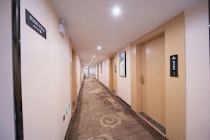 A hotel hallway with carpeted floors, wooden doors, and directional signs. - Zheng'an Manfei Hotel (Guitar Culture Squaie Branch) (Zheng'an)