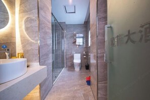 A modern bathroom with a glass shower enclosure, a white toilet, and a sink with a marble countertop.