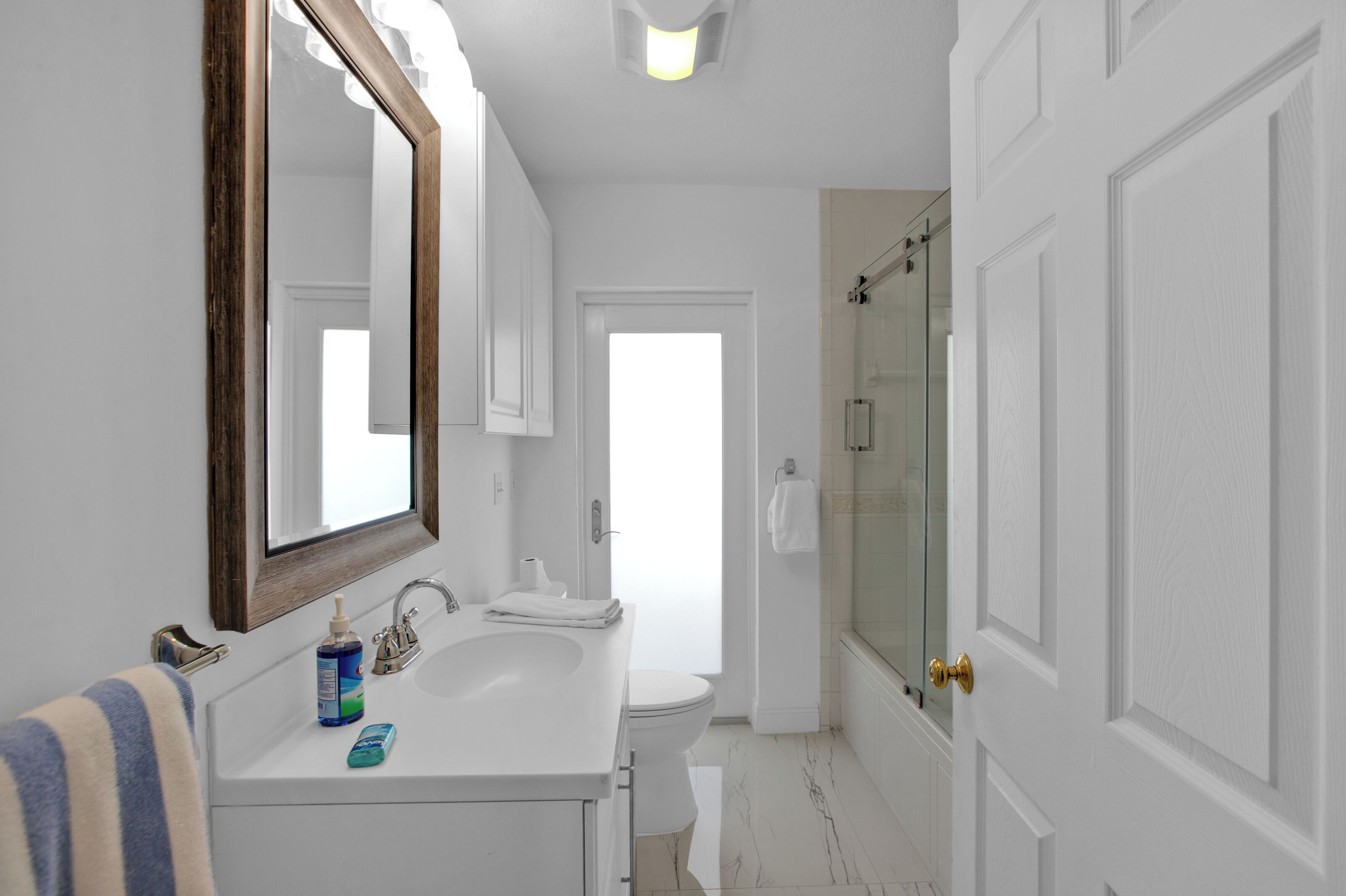 A modern bathroom with a large mirror, white sink, and a glass shower enclosure.
