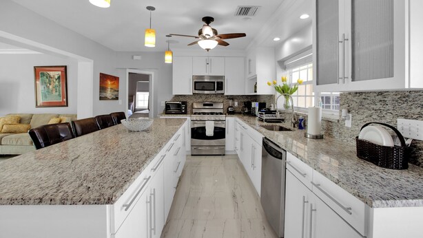 A modern kitchen with a large island, white cabinetry, and a ceiling fan. - Luxury Water Front, Heated Pool & Jacuzzi, 5br  (Pompano Beach)