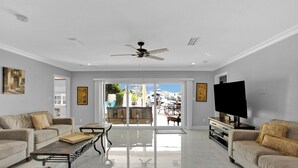 A spacious living room with a large TV, two sofas, a coffee table, and a ceiling fan. - Luxury Water Front, Heated Pool & Jacuzzi, 5br  (Pompano Beach)