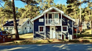 A two-story cabin with a balcony, surrounded by trees. - Villa Mar Baabe (Ostseebad Baabe)