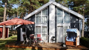 A modern house with a deck, outdoor seating, and a covered area with an umbrella. - Villa Mar Baabe (Ostseebad Baabe)