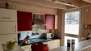 A kitchen with wooden cabinets, a microwave, and a bowl of fruit on the counter. - Villa Mar Baabe (Ostseebad Baabe)