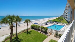 Un hotel con piscina, vista al mar y palmeras.