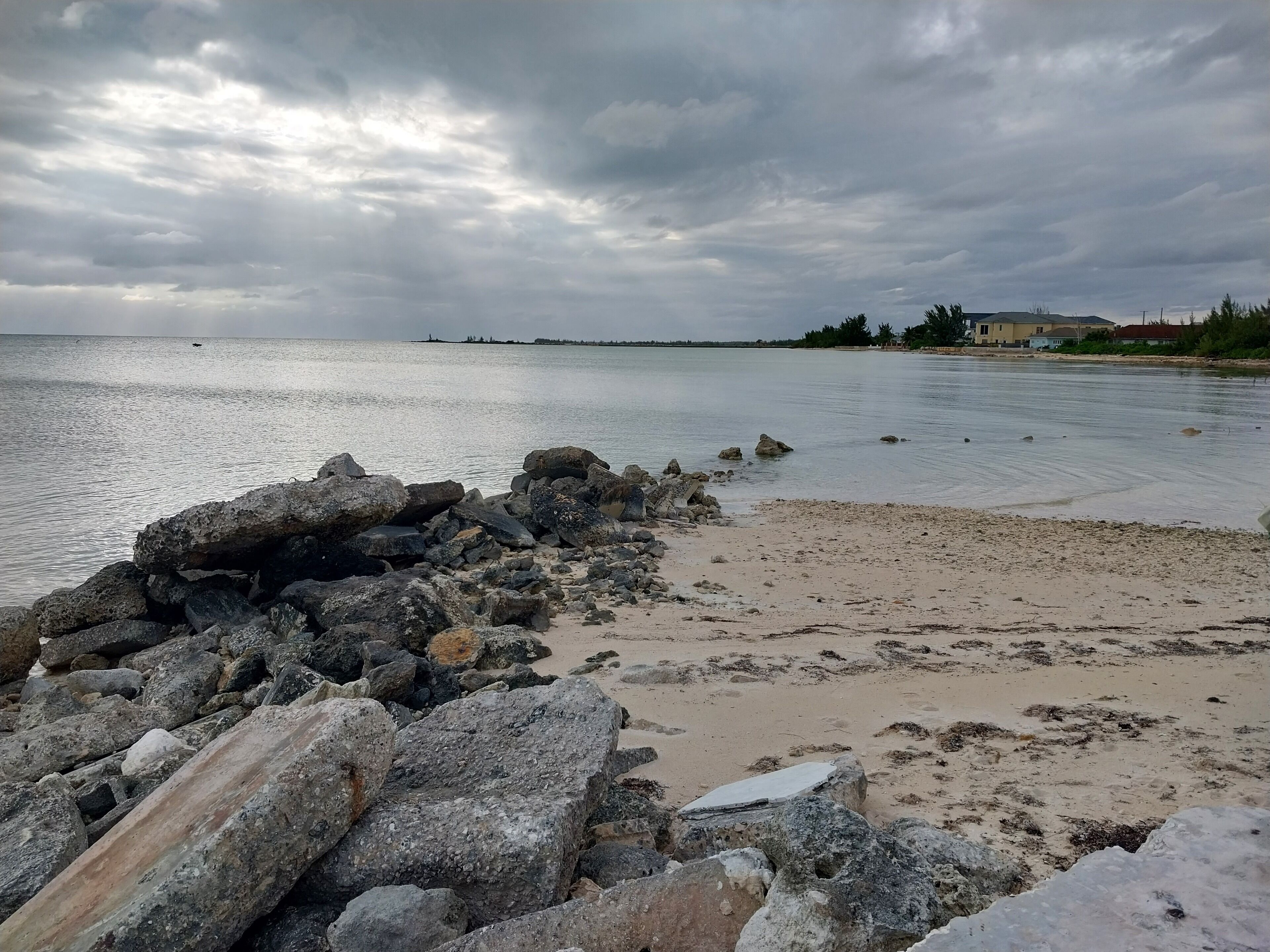 Kallioinen rantaviiva, jossa on hiekkaranta ja tyyni vesi.