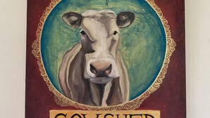 Une œuvre d’art murale représentant une vache, avec l’inscription « THE COW SHED ».