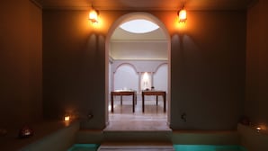 Een wellnessruimte met een zwembad, twee houten tafels en een plafondlamp.