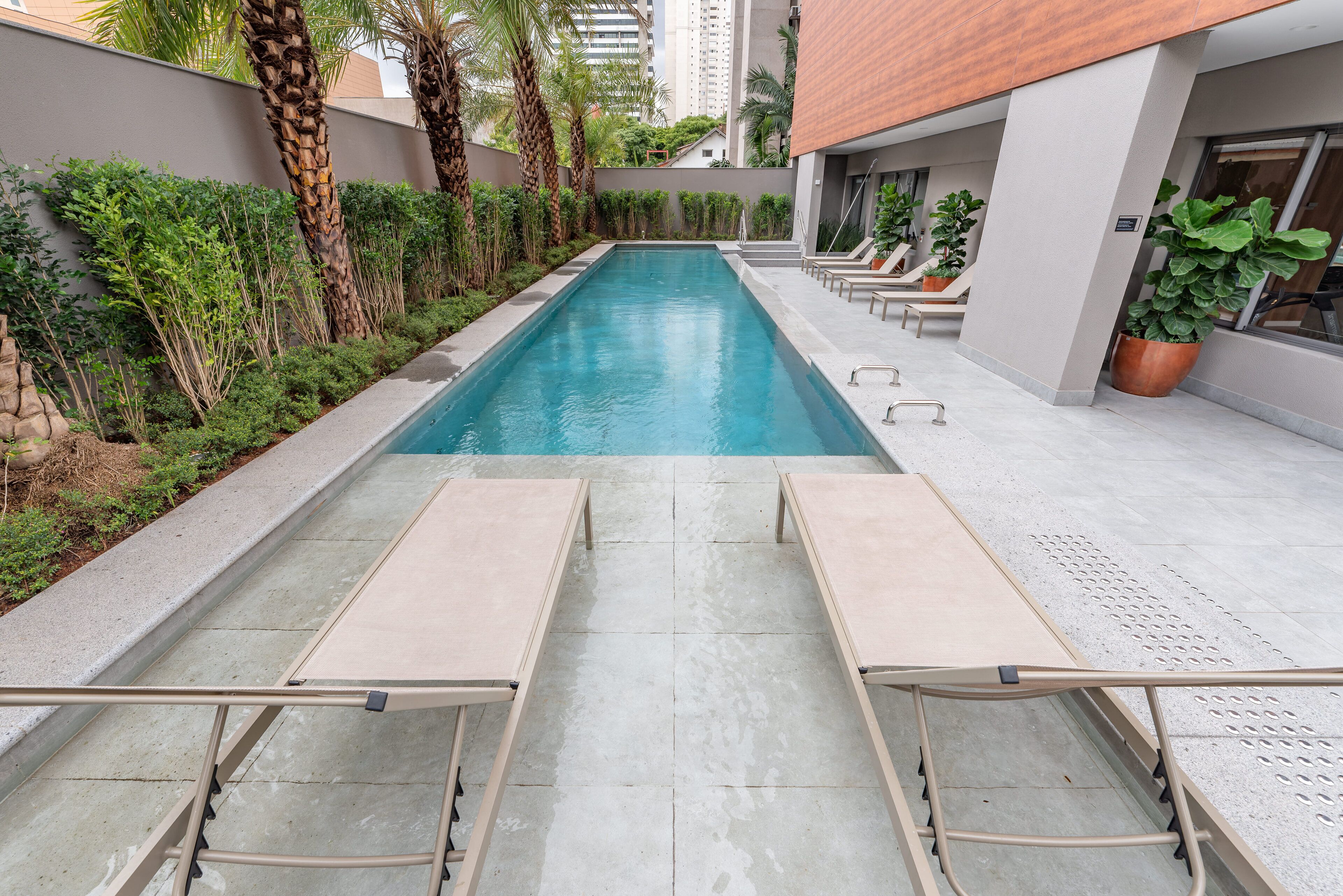 A swimming pool with lounge chairs and potted plants.