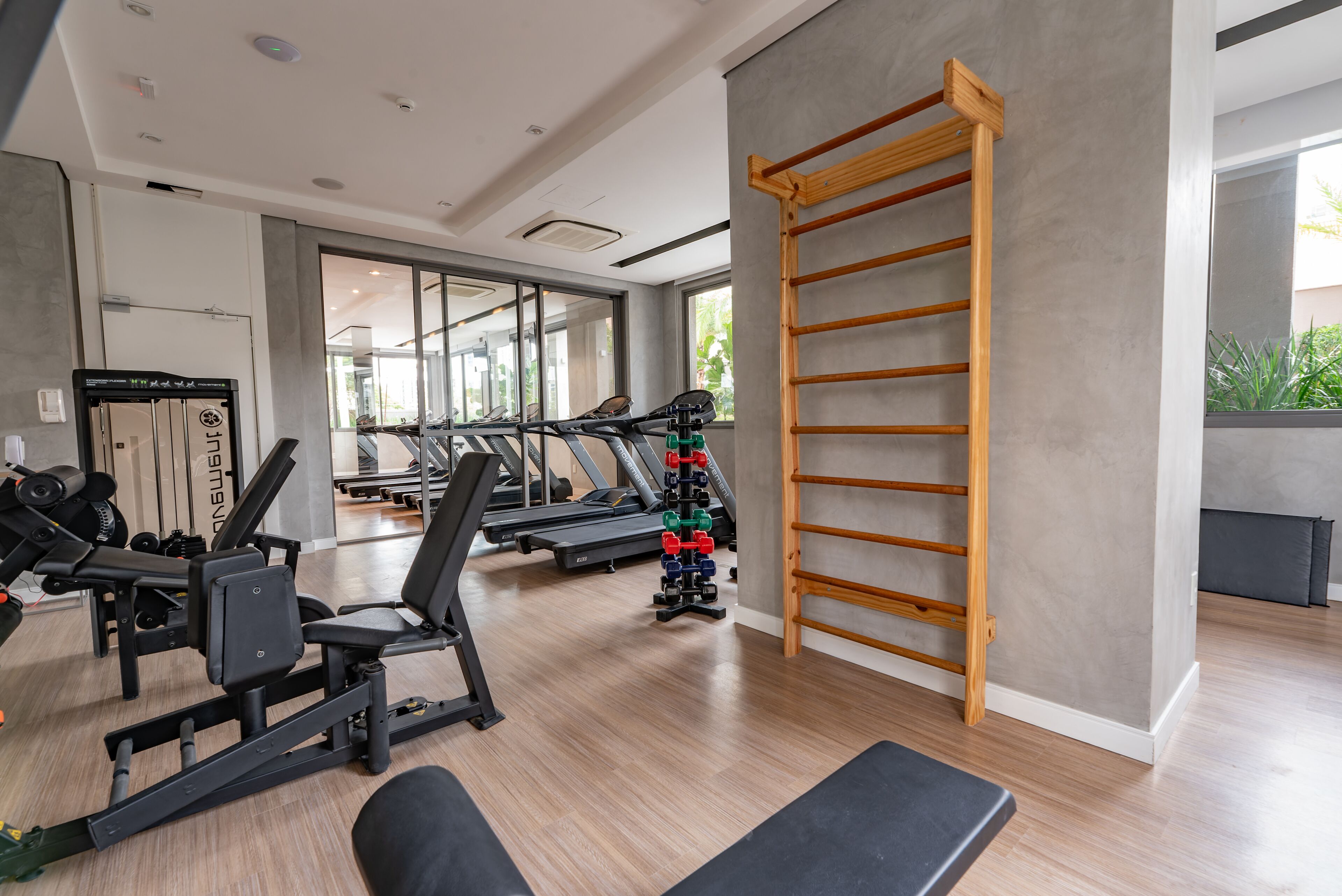 A modern gym with exercise equipment, a pull-up bar, and large windows.